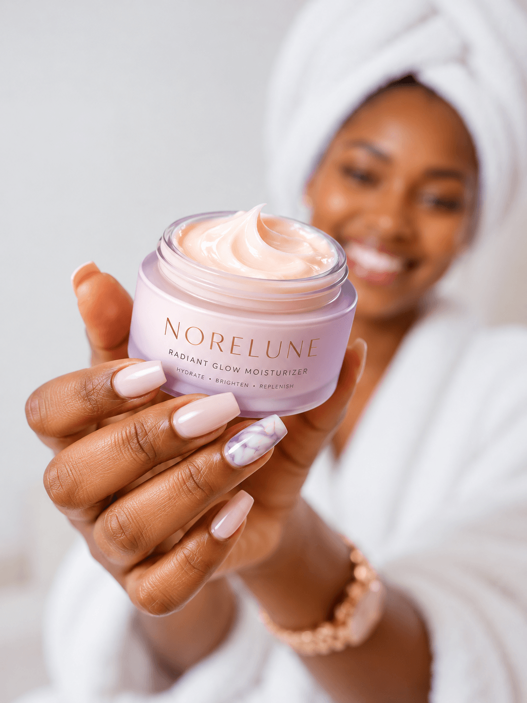 NoreLune radiant glow moisturizer held in a hand with a smiling person softly blurred behind